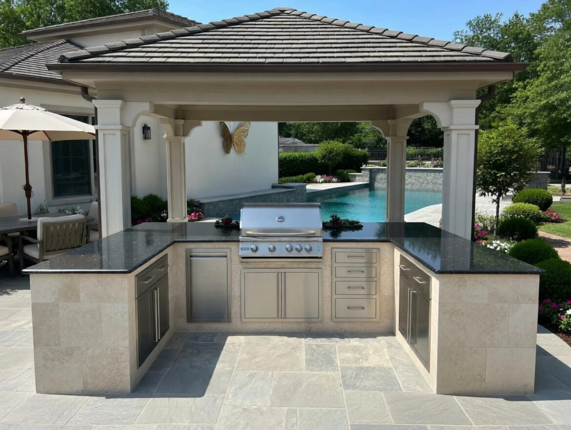 Custom outdoor kitchen with covered pavilion beside a pool, built by Hartwell Home Improvement